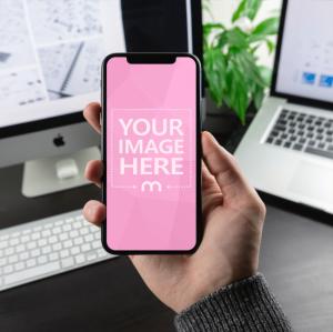 Man Holding iPhone X on Office Background Mockup Generator