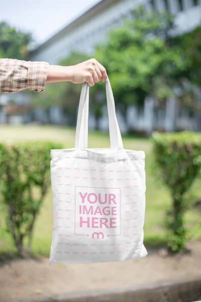 Mockup of a Tote Bag Featuring a Hand Holding it From the Side