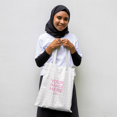 Mockup of a Tote Bag Hold Both Hands by a Smiling Woman