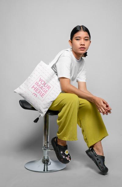 Mockup of Tote Bag Featuring a Confident Girl Sitting