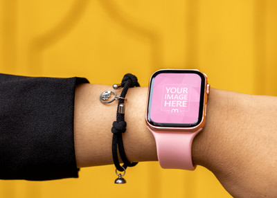 Pink Smartwatch Mockup Put on a Woman Hand on Yellow Background