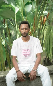 Shirt Mockup Featuring a Sitting Black Man Posing to the Camera